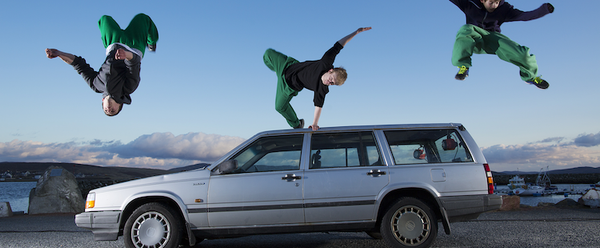 3 stunt jumpers with matching black hoodies and green joggers leaping from a car doing unique stunt poses.