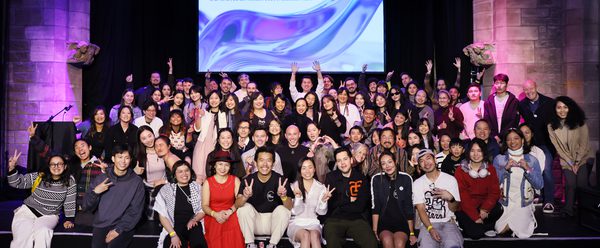 A large group of ESEA artists sit together smiling.