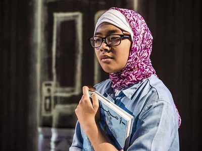 A girl wearing a headscarf holding a book