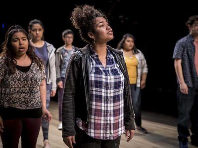 A group of people stand spaced apart, looking up