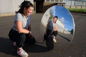Nic green kneels in front of a mirror, reflecting their image