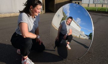 Nic green kneels in front of a mirror, reflecting their image