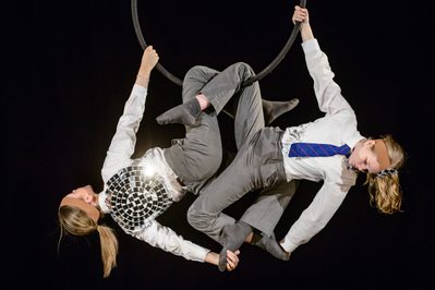Two school pupils are hanging from a hoop, supporting each other. One pupil has a disco ball on her back.