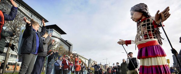 Crowds of schoolchildren wave to giant Little Amal puppet