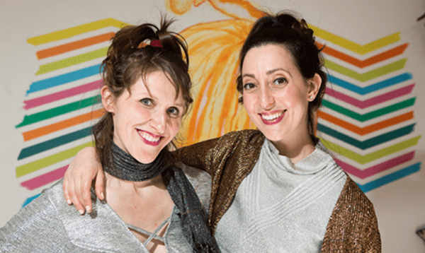 Two women with arms around each other, smiling