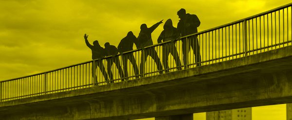 Six shadowed figures stand on an overpass some point and gesture. Most of the image is yellow.