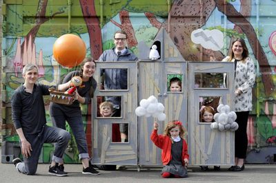 A group of adults and children holding props on a set