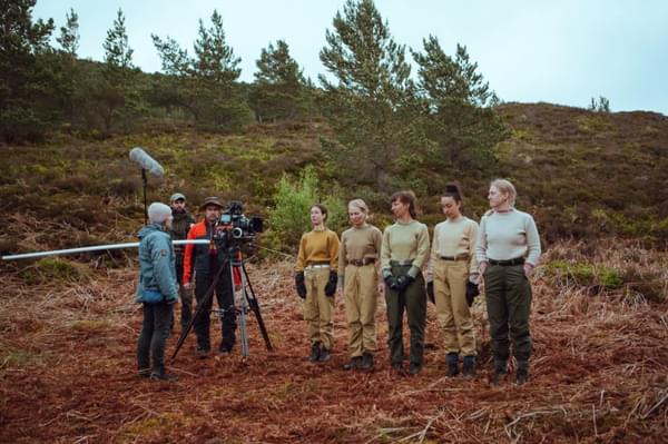 Five people standing in a line, being filmed in nature