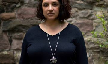 Woman in black top standing in front of brick wall