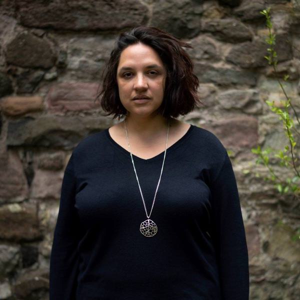 Woman in black top standing in front of brick wall