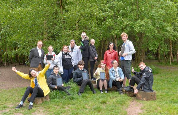 A group of young people in the park with trees behind them