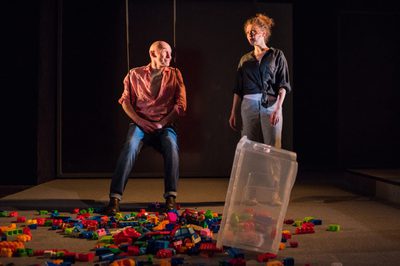 Man sitting on swing looking at woman, with children's building blocks on the floor