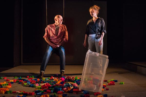 Man sitting on swing looking at woman, with children's building blocks on the floor