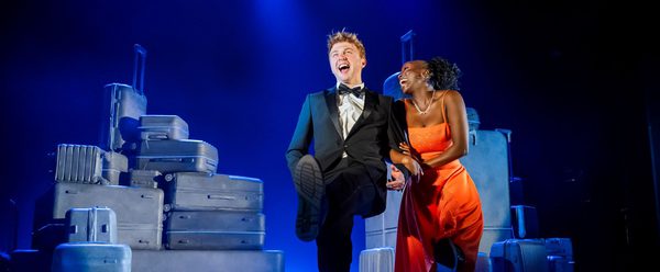 Two people in formal evening wear smile on a stage.