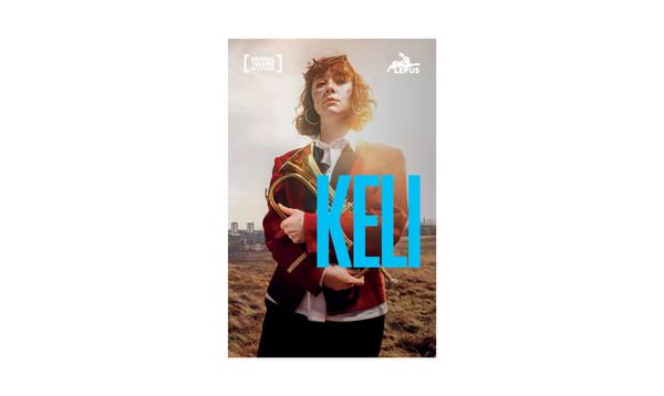 Image of KELI Playtext, featuring Liberty Black. She is wearing a red blazer and holds a Brass musical instrument
