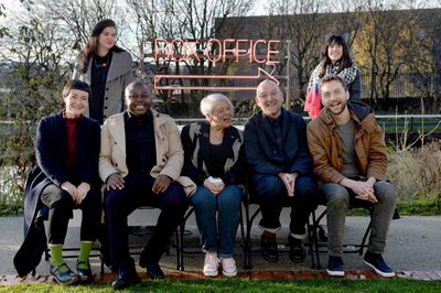 7 people gathered around a neon box office sign