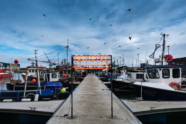 A neon box office sign on a harbour