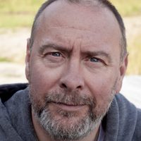 Barrie Hunter looks intently at the camera. He wears a grey hoodie.