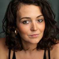 Anna Russell Martin has brown hair an earring is seen peeping out behind it.