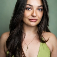 Actress Chiara Sparkes smiles to the camera she has brown hair and wears a trendy green top.