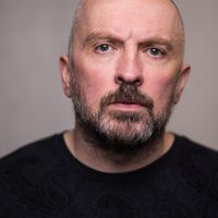 Keith Fleming is bald with a beard, he watched the camera intently.
