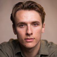 Lewis Fleming gazes at the camera, he wears a nice khaki shirt.