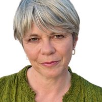 Shelley looks at the camera, she wears a green top and has short silver hair