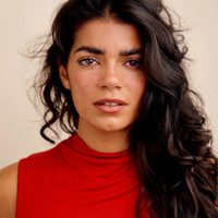 Shreya Khaund Marshall looks at the camera, she has brown hair and a red top.