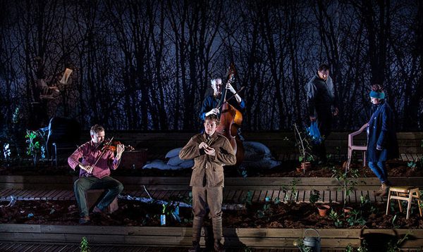 Five performers in an allotment with two playing string instruments