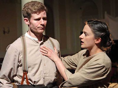 A man looks worried. A woman fixes his shirt.