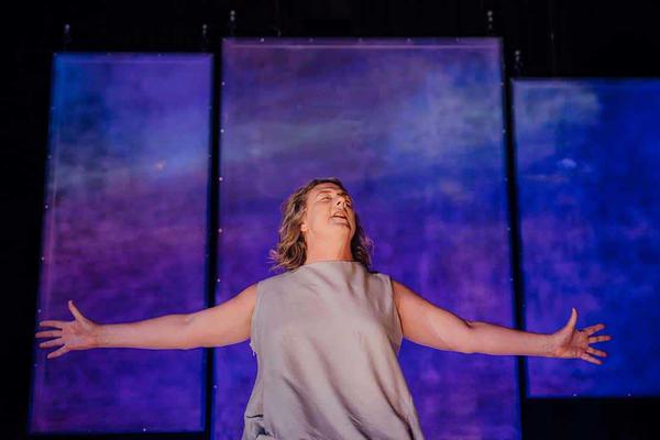 A woman stands with her arms held open