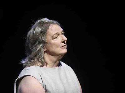 A woman with grey hair tilting her head to the side