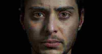 A young man with dark hair and light brown eyes looks forward, directly into the camera.