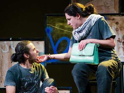 A woman and man look at one another, she holds his chin in her hands