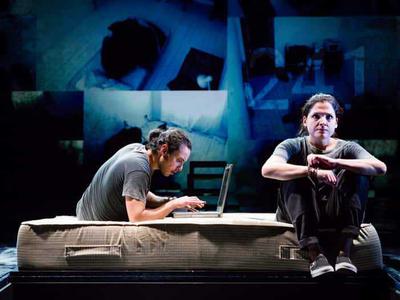 Glasgow Adam types on a laptop on an old mattress. Egyptian Adam glares into the distance.