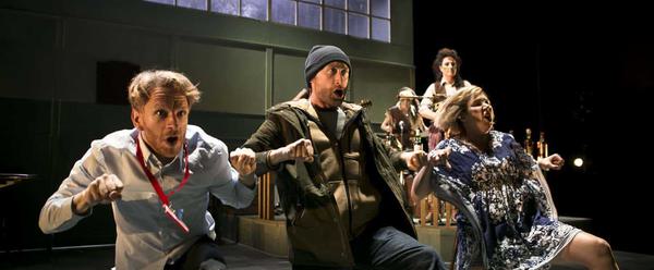 Three actors on bended knee, mid-song making a rowing motion with their hands.