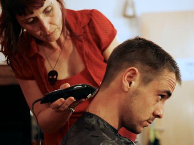 A crew member holds an electric shaver to the back of an actors head