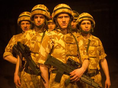 A company of soldiers stand close together, armed