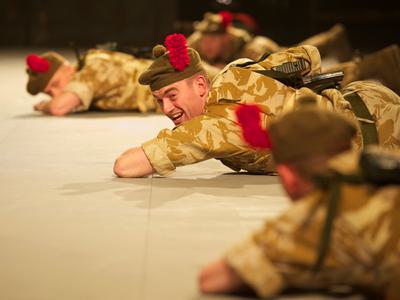 Actors crawl on their front in military outfits