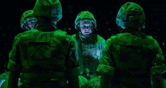 Four actors in military uniform gather together. They appear stressed