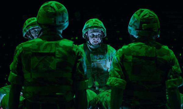 Four actors in military uniform gather together. They appear stressed