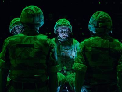 Four actors in military uniform gather together. They appear stressed