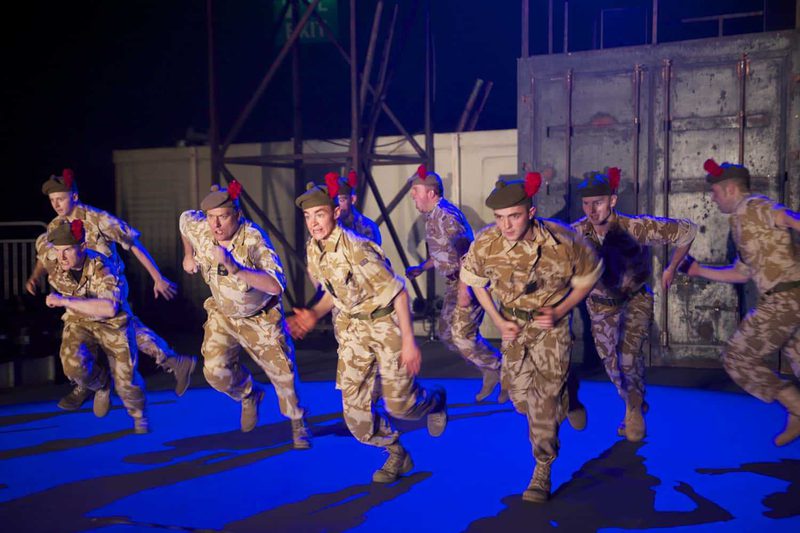A large group of actors in military clothing charge forward