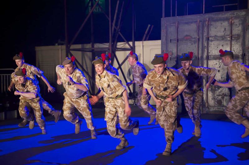A large group of actors in military clothing charge forward