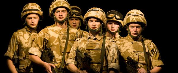 A group of actors in military attire stand at the ready