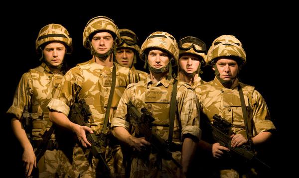 A group of actors in military attire stand at the ready