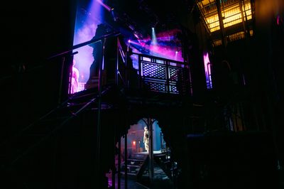 Looking onto the stage from behind the set of Dracula. There are performers on stage and bright pink and purple lights.
