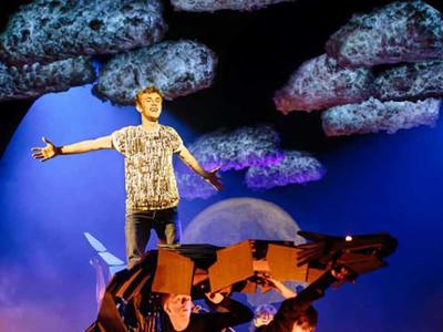 A young man rides a large dragon with a magical purple sky above him