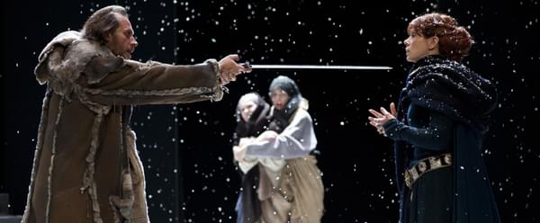 A man threatening a woman with a sword on a snowy set