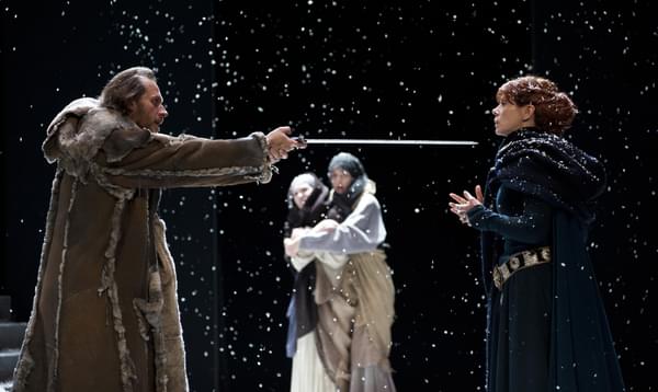 A man threatening a woman with a sword on a snowy set